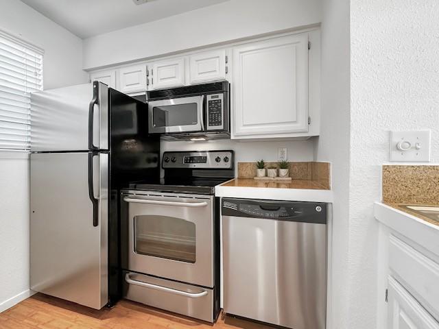 kitchen with white cabinetry, appliances with stainless steel finishes, and light hardwood / wood-style floors