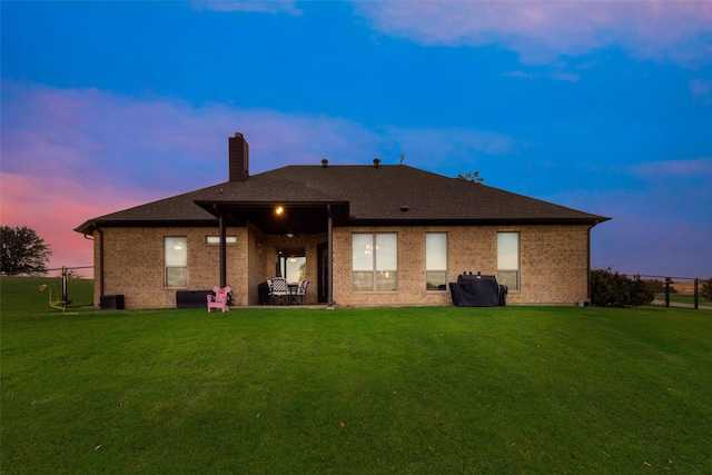 rear view of house featuring a yard, a chimney, and fence