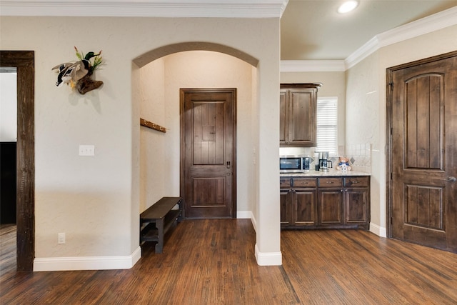 interior space featuring baseboards, ornamental molding, arched walkways, and dark wood-style flooring