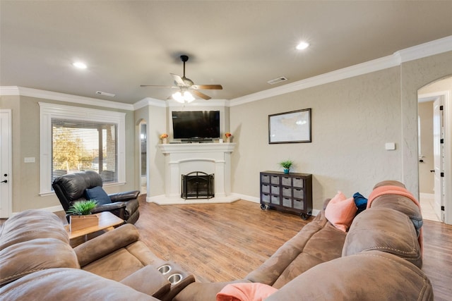 living area featuring arched walkways, wood finished floors, visible vents, and crown molding