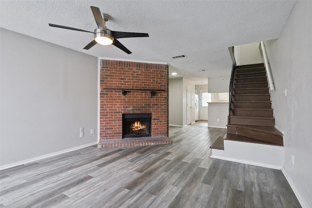 unfurnished living room with a brick fireplace, ceiling fan, a textured ceiling, and hardwood / wood-style floors