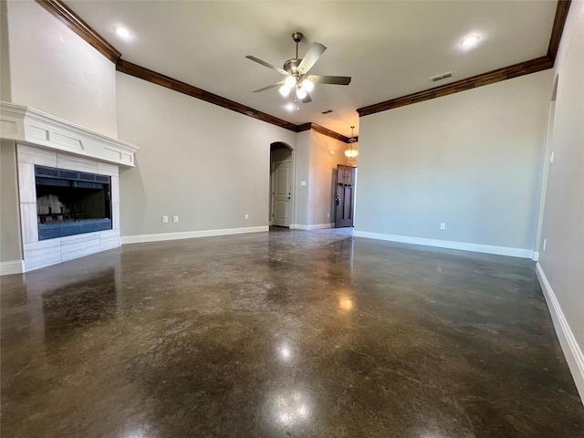 unfurnished living room with a tiled fireplace, crown molding, and ceiling fan