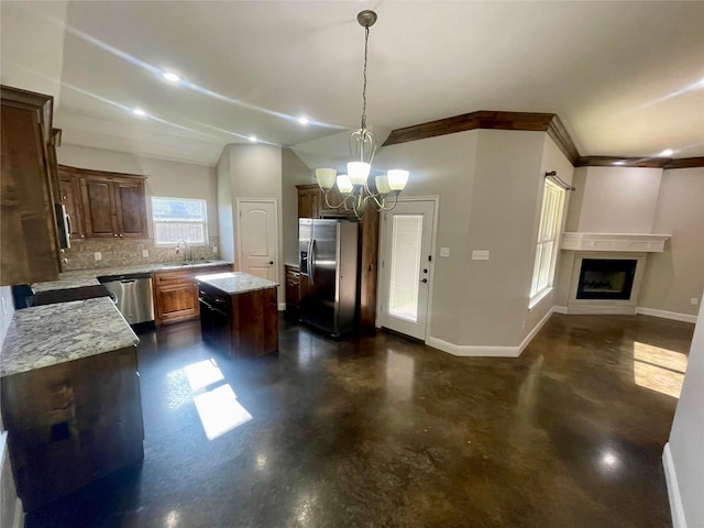 kitchen featuring a kitchen island, appliances with stainless steel finishes, backsplash, hanging light fixtures, and light stone countertops