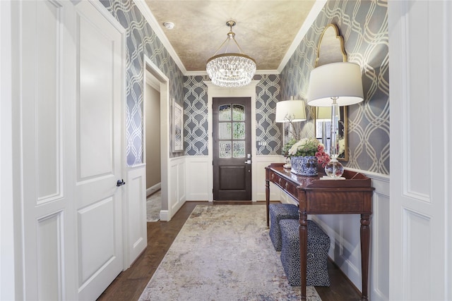 foyer featuring dark hardwood / wood-style flooring, ornamental molding, and a chandelier