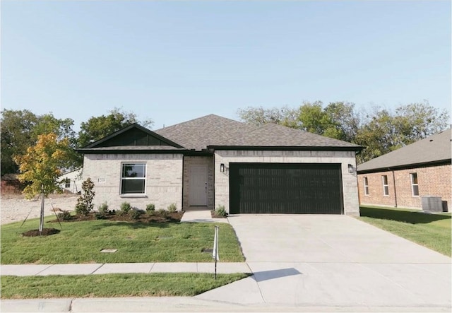 view of front of property featuring a garage, a front lawn, and central air condition unit