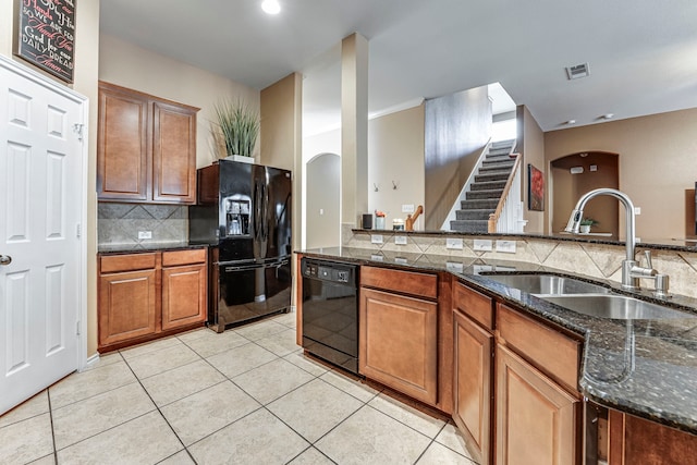 kitchen with sink, light tile patterned floors, black appliances, and dark stone counters