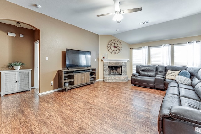 living room featuring hardwood / wood-style flooring, ceiling fan, a fireplace, and lofted ceiling