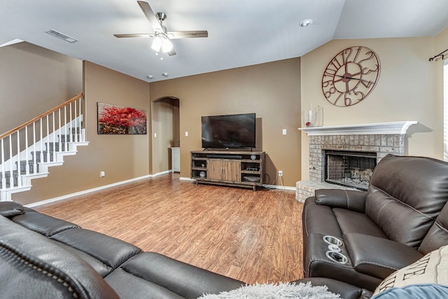 living room featuring ceiling fan, hardwood / wood-style flooring, vaulted ceiling, and a brick fireplace