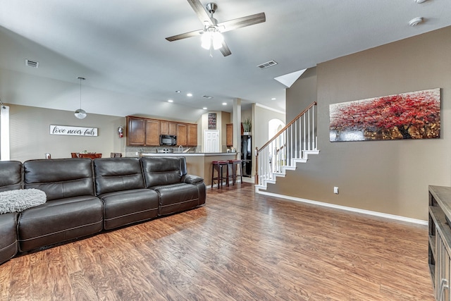 living room with light wood-type flooring, ceiling fan, and vaulted ceiling