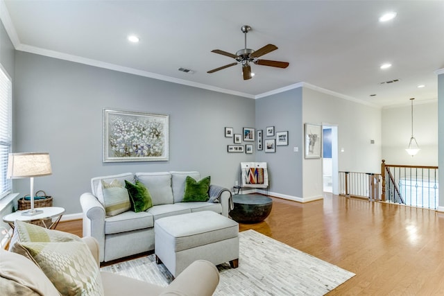 living room with ceiling fan, crown molding, and light wood-type flooring