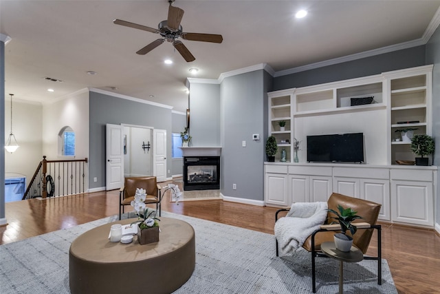 living room featuring a multi sided fireplace, ornamental molding, and hardwood / wood-style floors