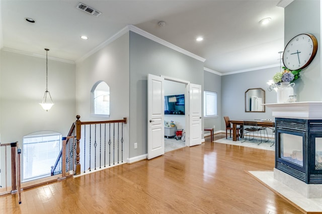 living room featuring wood-type flooring, a tile fireplace, and ornamental molding