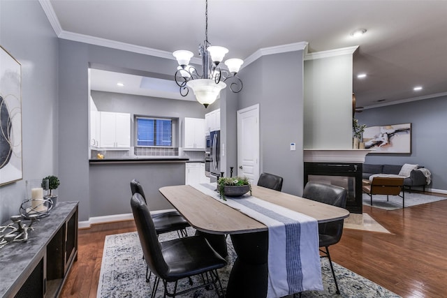 dining area featuring a notable chandelier, a multi sided fireplace, crown molding, and dark hardwood / wood-style flooring