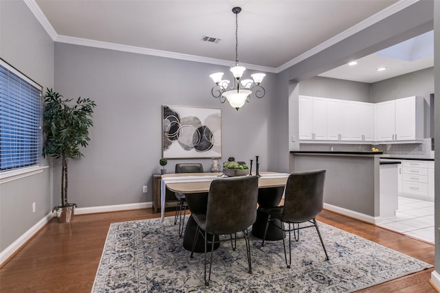 dining space with hardwood / wood-style flooring, ornamental molding, and a chandelier