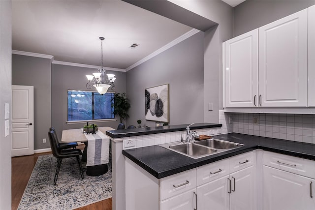 kitchen featuring a notable chandelier, sink, white cabinets, pendant lighting, and dark hardwood / wood-style floors