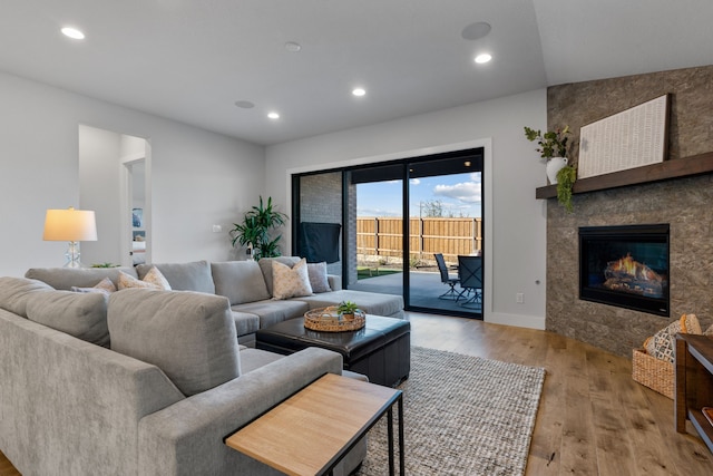 living room featuring light hardwood / wood-style flooring, a tile fireplace, and vaulted ceiling