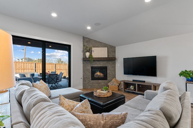 living room with hardwood / wood-style flooring, vaulted ceiling, and a large fireplace