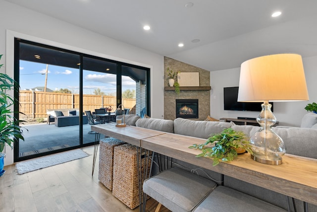 living room featuring a large fireplace, vaulted ceiling, light wood-type flooring, and recessed lighting