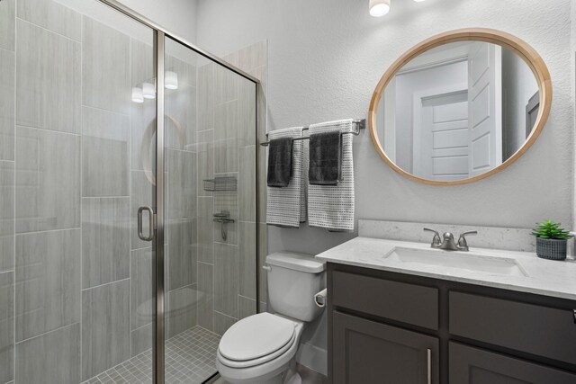 bathroom with toilet, a stall shower, and vanity