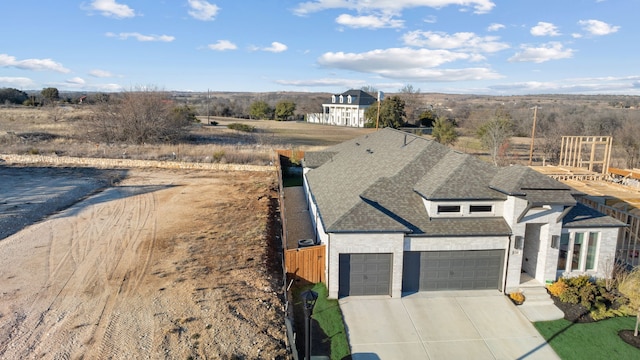 view of front of home featuring roof with shingles, brick siding, concrete driveway, fence, and a garage