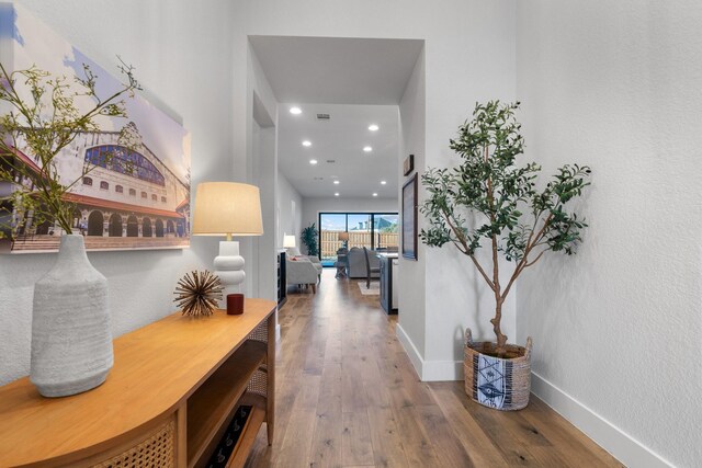 corridor with wood-type flooring, visible vents, baseboards, and recessed lighting