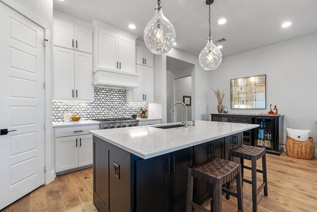 kitchen featuring sink, stainless steel appliances, white cabinets, a center island with sink, and decorative light fixtures