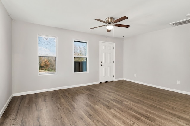 empty room with a ceiling fan, visible vents, baseboards, and wood finished floors