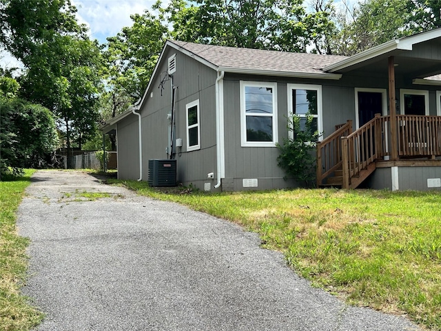 1206 W Hanna St, Denison, TX 75020 - view of side of property with crawl space, a shingled roof, asphalt driveway, and a lawn