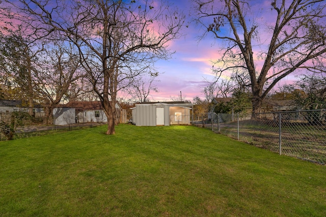 yard at dusk featuring a storage unit