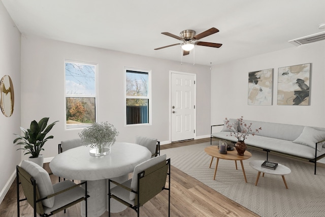 dining space with a ceiling fan, wood finished floors, visible vents, and baseboards