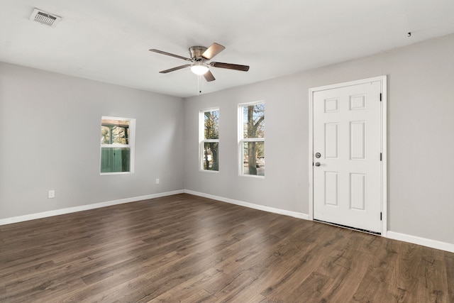 unfurnished room with a ceiling fan, visible vents, dark wood finished floors, and baseboards