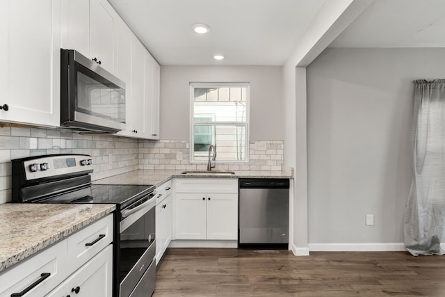 kitchen with a sink, appliances with stainless steel finishes, backsplash, light stone countertops, and dark wood finished floors