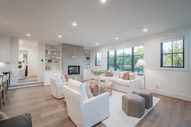 living room with a fireplace, light hardwood / wood-style floors, and built in shelves