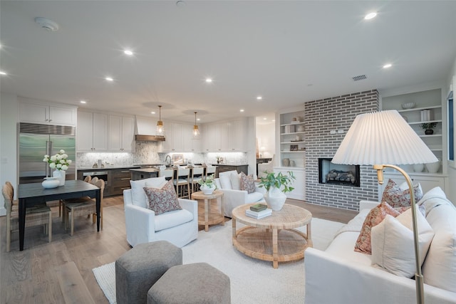 living room featuring a brick fireplace and light hardwood / wood-style flooring