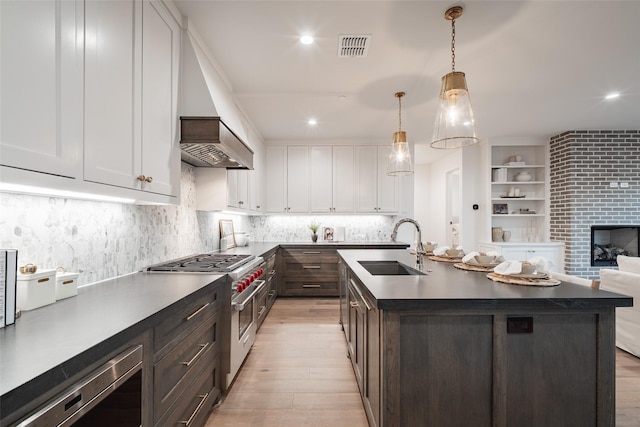 kitchen with high end stainless steel range oven, white cabinetry, dark brown cabinets, and sink