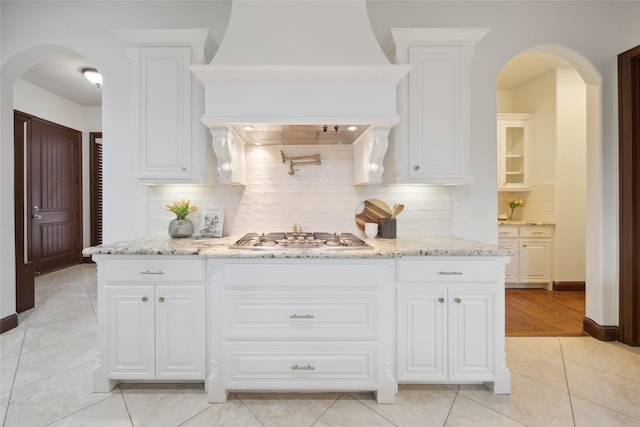 kitchen with stainless steel gas stovetop, white cabinetry, and backsplash