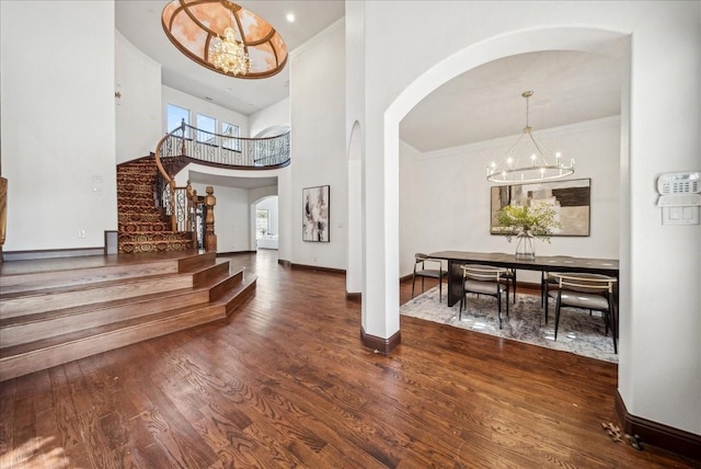 foyer entrance with crown molding, a chandelier, hardwood / wood-style floors, and a high ceiling