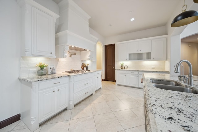 kitchen featuring sink, decorative backsplash, light stone countertops, and white cabinets