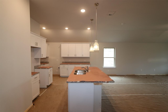 kitchen with hanging light fixtures, a center island with sink, white cabinetry, and a sink