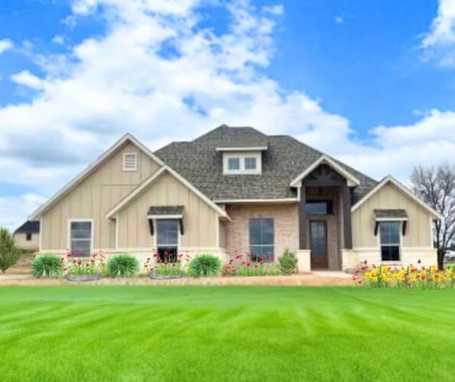 craftsman-style house with board and batten siding, a front yard, and a shingled roof