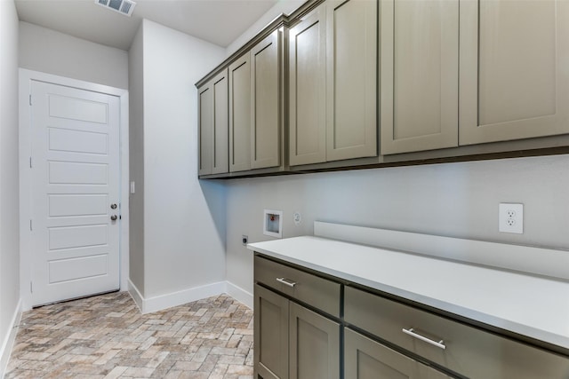 laundry area with hookup for a washing machine, baseboards, cabinet space, brick floor, and electric dryer hookup