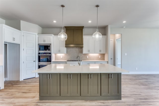 kitchen with light wood-style flooring, built in microwave, white cabinets, light countertops, and decorative backsplash