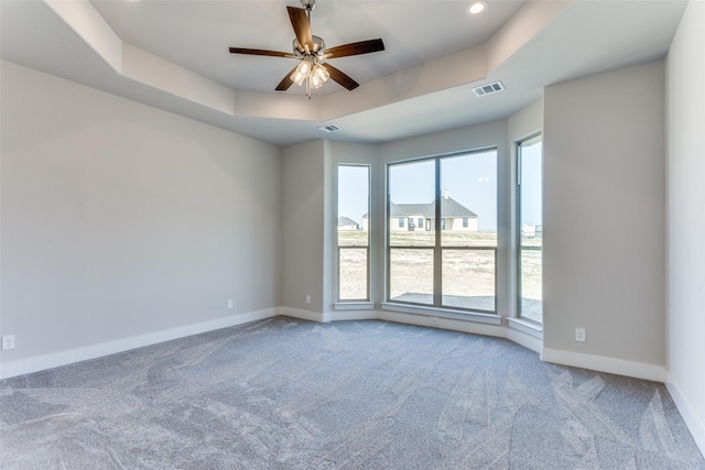 unfurnished room with visible vents, baseboards, ceiling fan, carpet flooring, and a raised ceiling