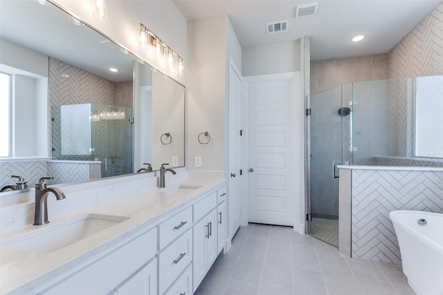 full bathroom with tile patterned flooring, a stall shower, a freestanding tub, double vanity, and recessed lighting