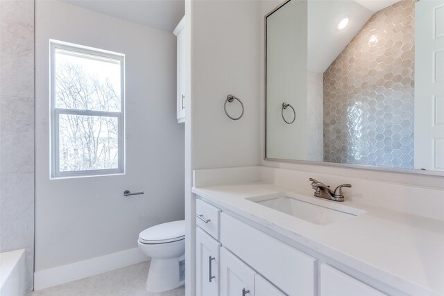 bathroom featuring toilet, baseboards, vanity, recessed lighting, and a bathtub