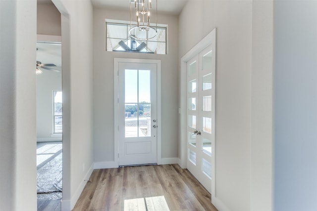 entryway with wood finished floors, baseboards, a wealth of natural light, and a chandelier