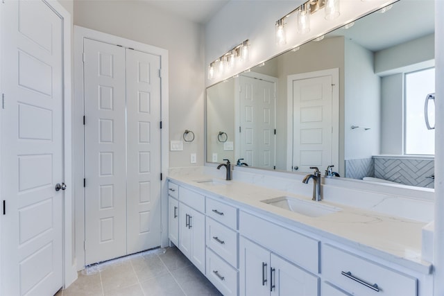 full bath with a sink, a closet, double vanity, and tile patterned floors