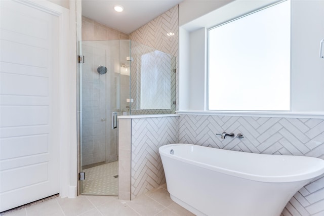 bathroom featuring a shower stall, tile patterned flooring, a freestanding tub, and tile walls