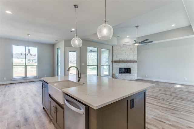 kitchen with a sink, a stone fireplace, ceiling fan, stainless steel dishwasher, and open floor plan