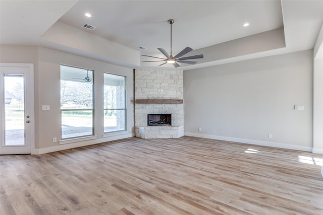 unfurnished living room featuring a tray ceiling, light wood-style flooring, plenty of natural light, and recessed lighting